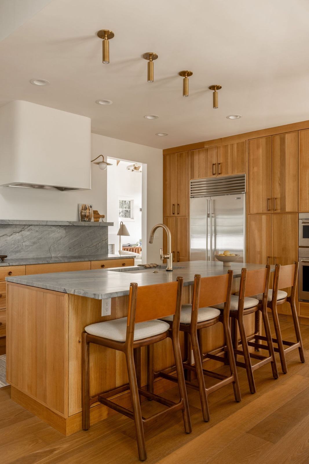Kitchen with brass cluster ceiling fixtures, gray marble slab backsplash, and leather-and-walnut barstools — Damn Good Interiors interior design, Boulder, CO