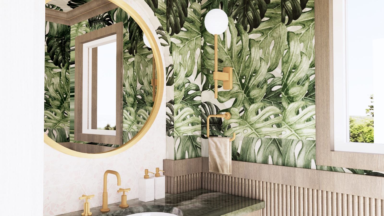 Powder room with bold tropical monstera-leaf wallpaper, a round brass-framed mirror, a brass globe sconce and cross-handle faucet, a green marble vanity top, pink terrazzo backsplash, and a fluted wood vanity — Damn Good Interiors interior design, Bryn Mawr, PA