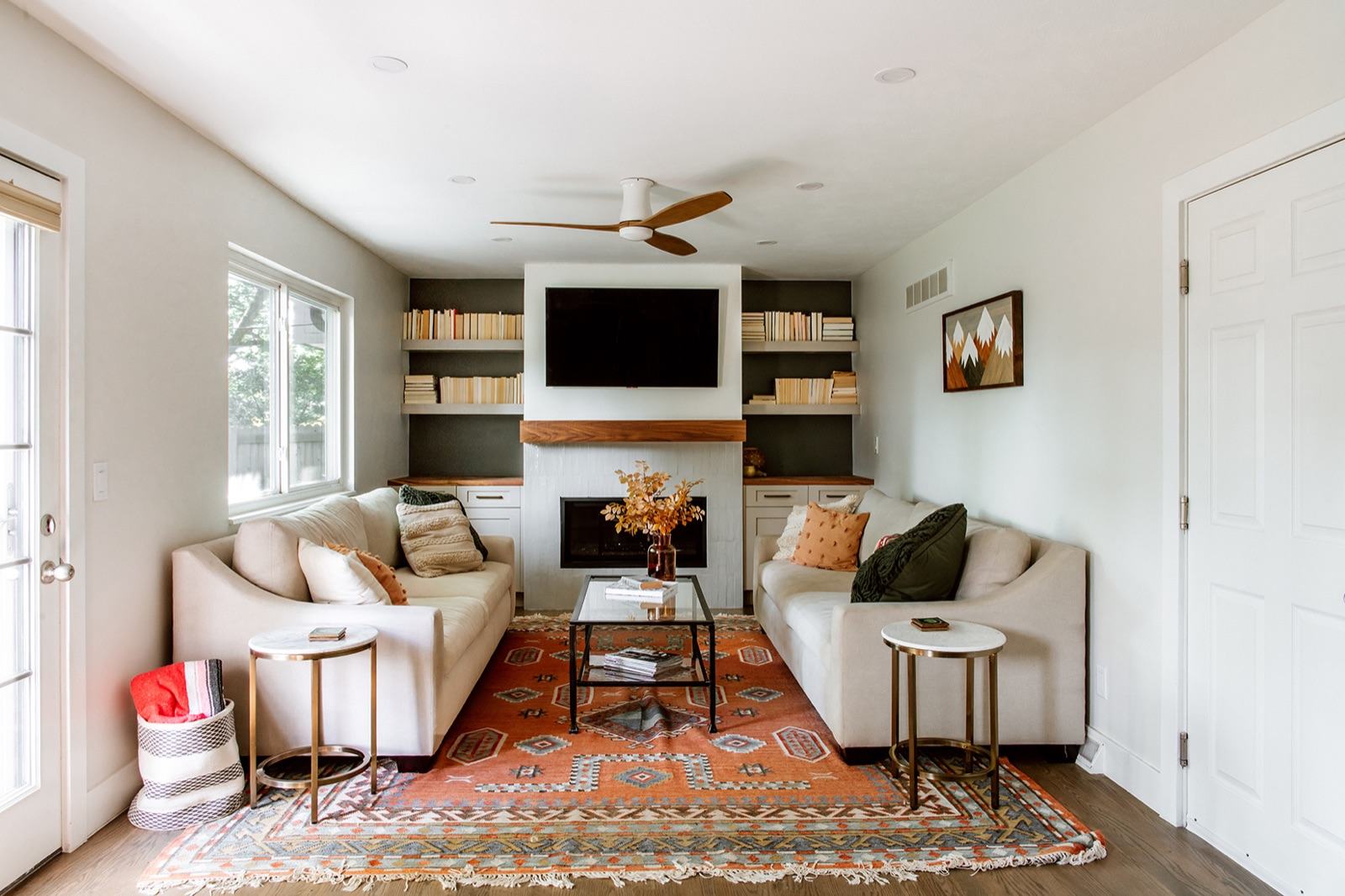 Living room with symmetric sofas, built-in bookshelves flanking the fireplace, and a Southwestern-pattern rug — Damn Good Interiors interior design, Centennial, CO